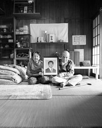 写真・福島第一原発で事故死した息子の遺影を持つ両親