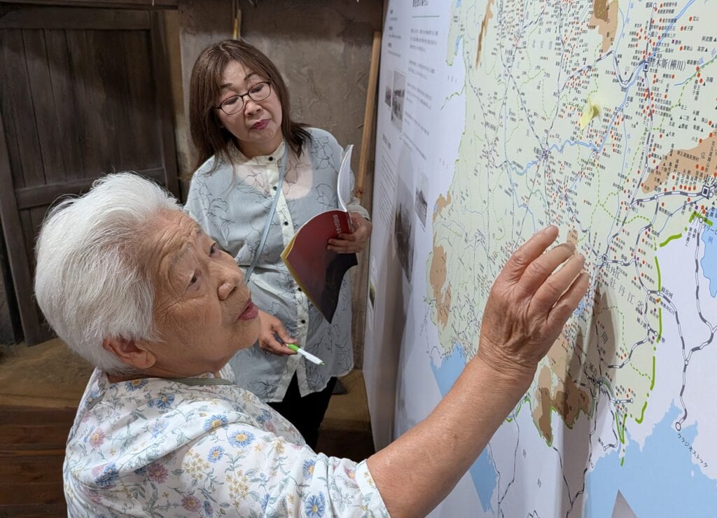 旧「満州国」の地図で開拓団の合った場所を探す北村栄美さんら